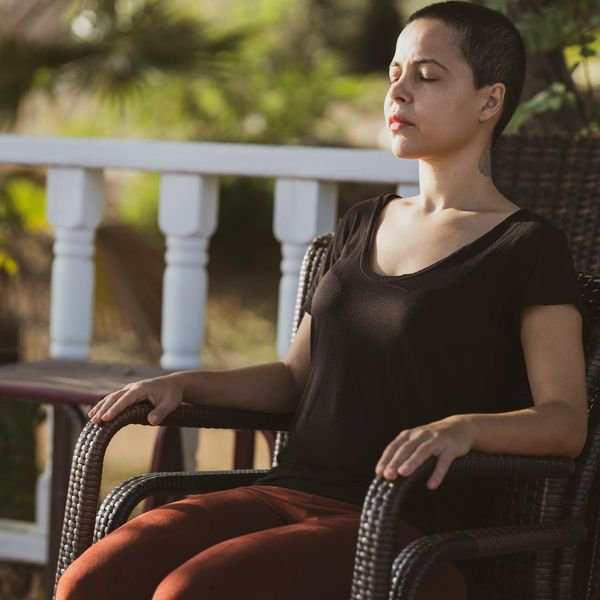 Person sitting peacefully in a meditative pose outdoors at sunrise.